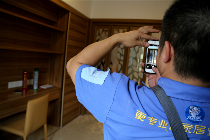 謝師傅看著(zhù)安裝好的家具，拍下照片
