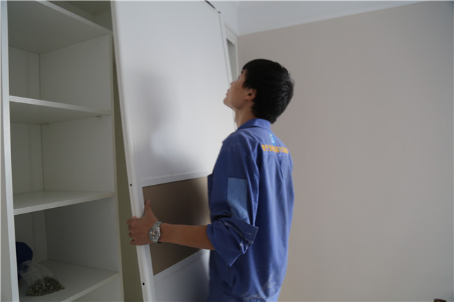 左右手家具安裝師傅正在調試衣柜門(mén)